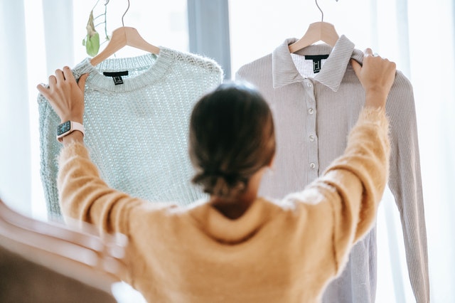 Vrouw met twee truien in haar handen